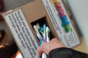 toothbrushes being put in a TerraCycle box for recycling put out by the dental hygiene studio